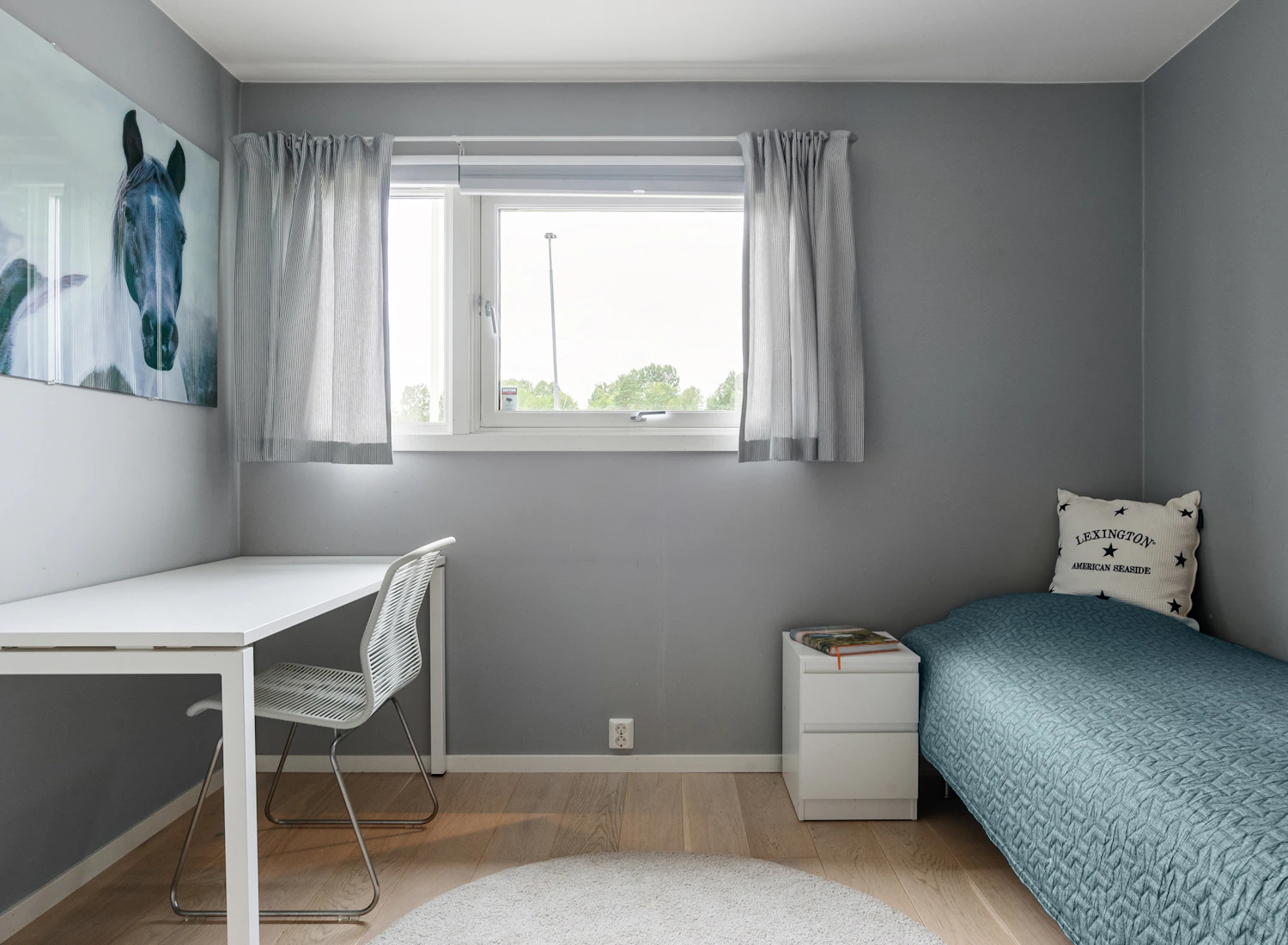 A furnished bedroom with a desk and bay window