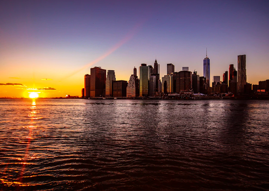 Lower Manhattan skyline reflected across the water at sunset
