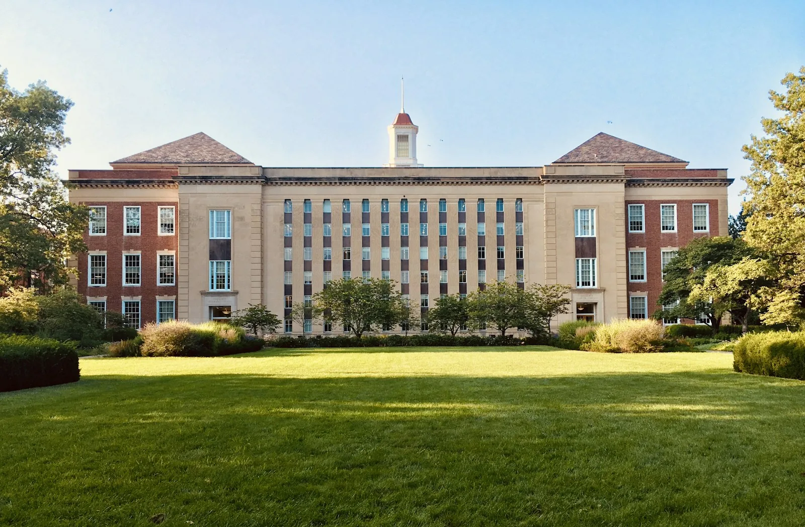 A brick campus building beyond a green lawn